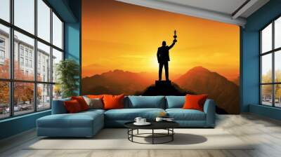 Silhouette of a businessman holding a trophy on top of a mountain with the sunset. The concept of a successful business or great executive to lead the organization to success. Wall mural