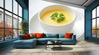 A bowl of yellow soup with a green herb on top. The soup is creamy and looks delicious Wall mural