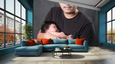 family portrait of young asian dad whit his boy newborn in black background . Wall mural