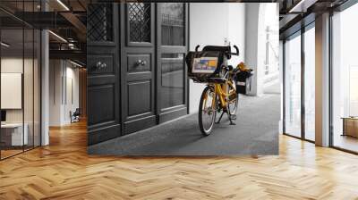 A postman's bike parked in front of the entrance of a building in town in France Wall mural