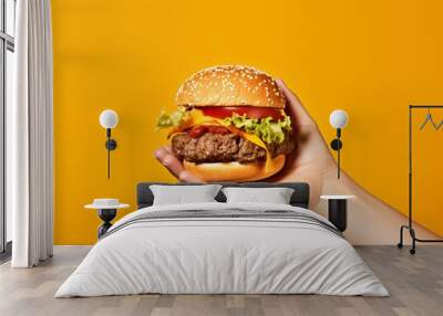 Hands holding a burger yellow background Wall mural