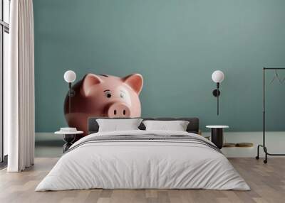 A pink piggy bank surrounded by gold coins against a grey backdrop, symbolizing financial savings or the accumulation of wealth Wall mural