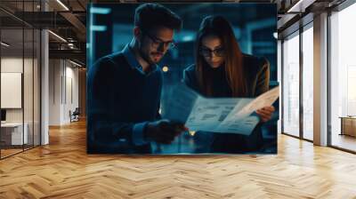 .Two business people, a business man and a business woman, engage in a discussion as they read a financial report together. Young business professionals working together in a modern finance company. Wall mural