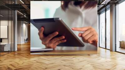 Businesswoman holding tablet and used to work online on the table at office. Wall mural