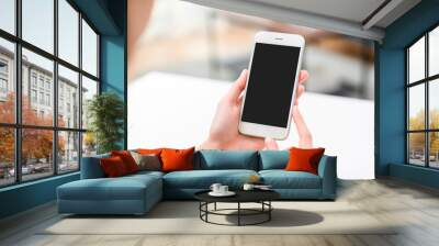 Hand holding smartphone mockup of blank screen on the table. Take your screen to put on advertising. Wall mural