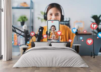 Vlogger live streaming podcast review on social media, Young Asian woman use microphones wear headphones with laptop record video. Content creator concept. Wall mural