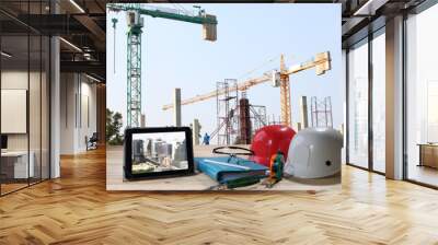 file of safety helmet and safety glasses on wood table in front of building construction background Wall mural