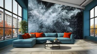 A vibrant explosion of silver powder erupts against a stark black background, creating a mesmerizing cloud of particles that dance and swirl in mid-air. grey white powder explosion on a black. Wall mural