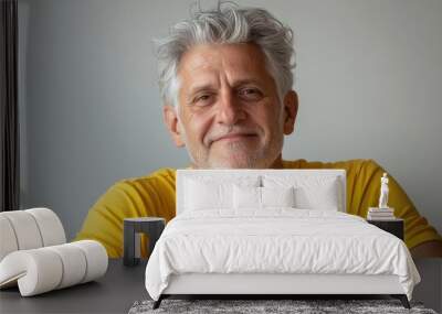 Close up of mature man with white skin, grey short hair, wavy hair and a clear yellow t shirt, isolated in a light grey studio. Portrait person. Wall mural