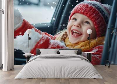 Happy little girl watching and playing with snow from an open car window on the trip of a snowy winter holiday, joyful kid have fun with snow flakes. Wall mural