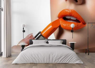 woman applying orange lip colors to her cute pout lips with a luxury orange lipstick isolated on white background Wall mural