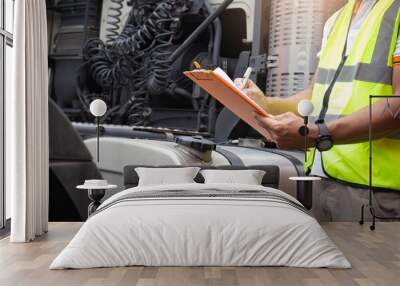 Maintenance and repairing. A truck driver holding clipboard checking safety a large fuel tank of semi truck. Wall mural