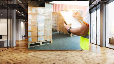 Worker holding clipboard inspecting checklist of packaging boxes. shipment boxes. supply chain. goods pallets loading with cargo container at dock warehouse. freight truck transport  logistics. Wall mural