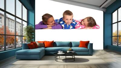 Three children laying down in their winter pajamas Wall mural