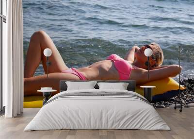 Happy woman in bikini lying on air bed on the beach Wall mural