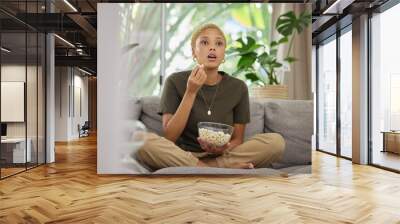 Surprise, watching tv and a woman on the sofa with popcorn for a movie or show. Wow, house and a young girl eating a snack while on the living room couch for a horror, film or streaming a drama Wall mural