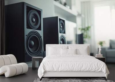 Two black bookshelf speakers on a shelf in a modern living room with a couch and a plant in the background. Wall mural