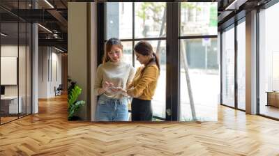 The two Asia use phone see content Social media Front window in coffee shop. Wall mural