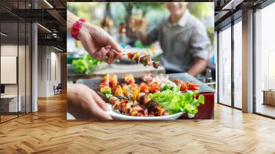 A man with a barbecue plate at a party between friends. Food, people and family time concept. Wall mural