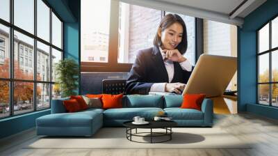 Closeup of businesswoman using laptop at office desk. She searching web or browsing information. Wall mural