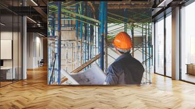 Engineer or foreman with blueprint in building construction site Wall mural