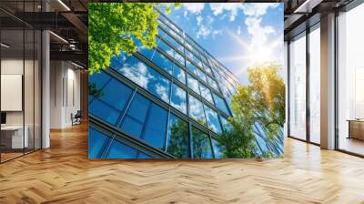 A modern office building with glass windows and trees in front, under the bright sunlight against a blue sky Generative AI Wall mural