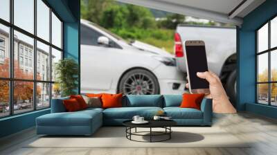 Hand of woman holding smartphone and take photo of car accident Wall mural