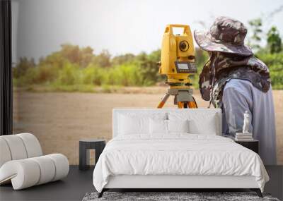 Surveyor engineer making measure at the land Wall mural