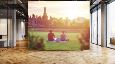 Two of tourist sitting in Sukhothai Historical Park at Sunset time, Sukhothai province, Located in a beautiful setting of lawns, lakes and trees in north-central, Thailand Wall mural