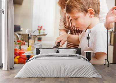 Small boy cooking together with his mother in the kitchen Wall mural