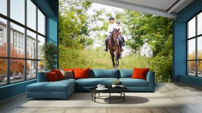 Two rider woman on horses going down from the hill. Equestrian summer activities background Wall mural