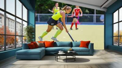 Young hockey player woman with ball in attack playing field hockey game Wall mural