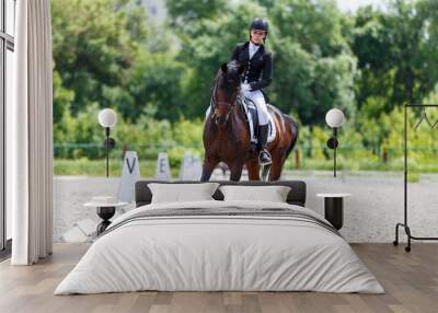 Young woman riding horse on dressage advanced test Wall mural