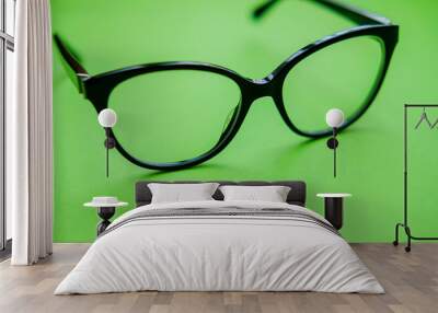 Black frame eyeglasses on green background. Myopia (nearsightedness), Short sighted or presbyopia (Farsightedness) eyeglasses.  Close up Wall mural