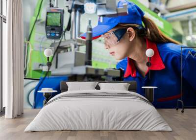 A female diesel engine mechanic in a blue uniform is working at the garage. Inspect and maintain the fuel pressure booster pump system and common rail injectors. Wall mural