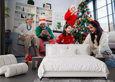 Asian family on Christmas Day. Everyone is happy together in a Christmas themed room filled with presents and orange lights. Wall mural