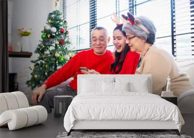 Asian family on Christmas Day. Everyone is happy together in a Christmas themed room filled with presents and orange lights. Wall mural