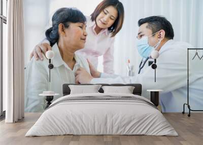 elderly Asian woman comes see the doctor for a check-up at hospital with daughter as follower are being examined for lung and heart function Doctors wear masks The idea take care of elderly patients Wall mural