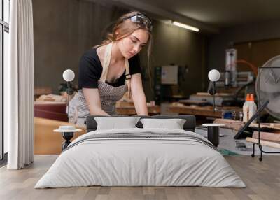 Portrait of a female carpenter drawing on paper for designing and building furniture in a furniture factory. with modern tools Wall mural