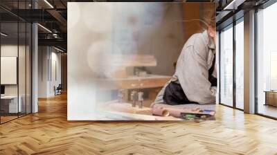 web banner Portrait of a female carpenter looking at designs on a tablet for making her furniture in a furniture factory. with many tools and wood with modern tools with copy space on left Wall mural