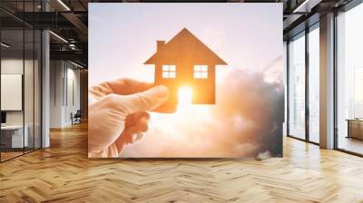 Man's hand holds wooden flat house against the sun Wall mural