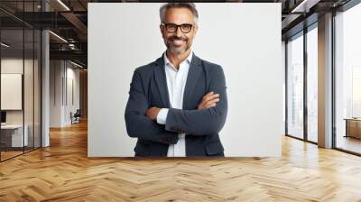 The businessman confidently stands with his arms crossed isolated, with stylish glasses and a charming smile. Perfect image for corporate profiles, professional services advertisements Wall mural