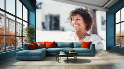 An outdoor portrait of a dazzling happy plus-size Hispanic female with curly hair; a laughing mature caucasian woman with a perfect white smile sitting in a street cafe on a warm sunny day Wall mural