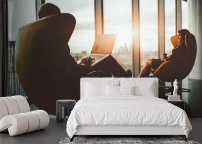 silhouettes of two business partners sitting in front of each other on curved yellow armchairs on th Wall mural