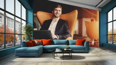 young smiling successful man entrepreneur in formal business suite with a beard sitting on orange ar Wall mural