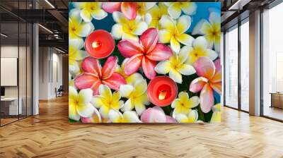 Many frangipani flowers with two red candle in the blue water Wall mural