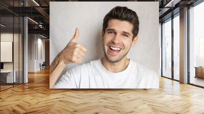 Portrait of a happy gorgeous man showing his thumb UP with a beautiful smile  Wall mural