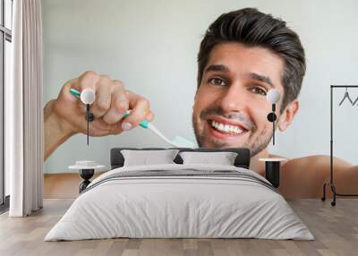 Young handsome latin man having a wide smile with a toothbrush in the bathroom  Wall mural