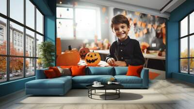 Happy laughing boy making paper halloween pumkin in classroom Wall mural