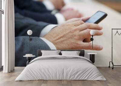 Man in a business suit uses a mobile phone - a smartphone, sitting next to colleagues during a business meeting or negotiations. Unrecognizable, without a face. Photo. Selective focus Wall mural